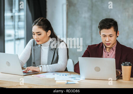 Konzentrierte sich die jungen kasachischen Geschäftsleute mit Laptops am Arbeitsplatz Stockfoto