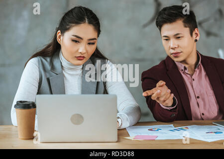 Junge kasachische Geschäftsleute mit Laptops und Arbeiten mit Dokumenten in Office Stockfoto