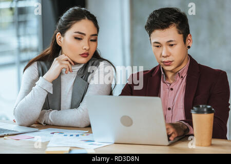 Junge asiatische Geschäftsleute arbeiten mit Laptop und Unterlagen im Büro Stockfoto