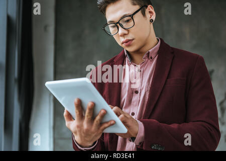 Schwerpunkt junger Mann in Brillen mit digitalen Tablette im Büro Stockfoto