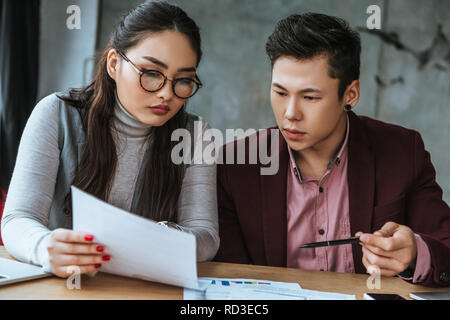 Konzentrierte sich jungen asiatischen Kollegen an Papiere im Büro suchen Stockfoto