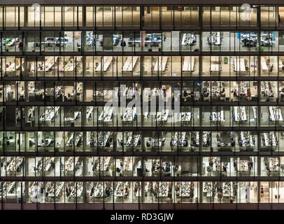 London, Großbritannien. Mitarbeiter im Büro in der Nacht, durch die Fenster eines Bürogebäudes in der Stadt, der Londoner Financial District gesehen Stockfoto