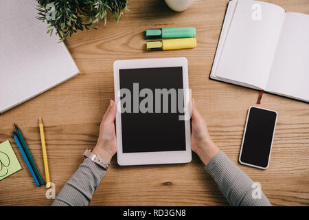 Blick von oben auf die geschäftsfrau Holding digital Tablet am Arbeitsplatz mit Smartphones und Notebooks Stockfoto