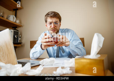 Gefühl krank und müde. Der Mann mit der Tasse heißen Kaffee im Büro, Geschäftsmann gefangen kalt, saisonale Grippe. Pandemic Influenza, die Prävention, Klimaanlage im Büro verursachen Krankheit Stockfoto