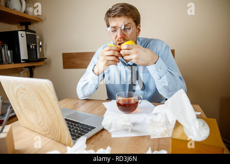 Gefühl krank und müde. Der Mann mit Zitrone und heiße Tasse Tee arbeiten im Büro, Geschäftsmann gefangen kalt, saisonale Grippe. Pandemic Influenza, die Prävention, Klimaanlage im Büro verursachen Krankheit Stockfoto