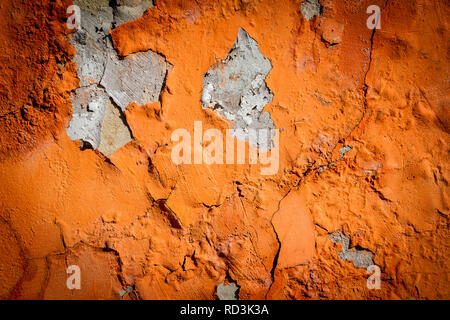 Orange Putz blättert von einer alten Mauer. Alt, dreckig geschält Pflasterwand mit aus fallenden Flocken von Farbe. Textur, Muster, Hintergrund. Stockfoto