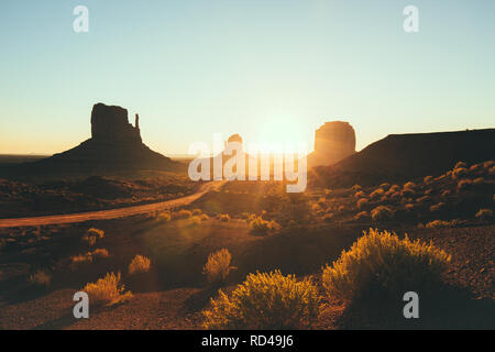 Klassische Ansicht der malerischen Monument Valley mit dem berühmten Mittens und Merrick Butte in wunderschönen goldenen lichter Morgen bei Sonnenaufgang im Sommer, Utah, USA Stockfoto