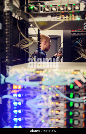 Junger Mann Techniker arbeiten mit Netzwerk Hardware. Fokus auf den Menschen Stockfoto