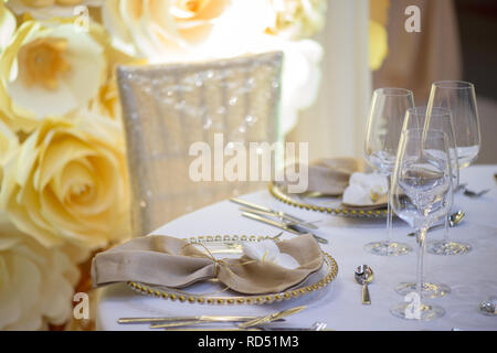 Sitzplatz in einer feierlichen Veranstaltung oder Fine Dining Restaurant mit transparenten Platten mit goldenen Details, Gläser und Besteck Stockfoto