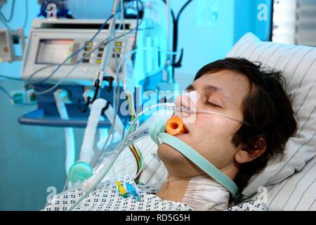 Patient in ein spezielles Bett, intubiert, medizinische Geräte für die medizinische Behandlung und künstliche Beatmung des Patienten, Stockfoto