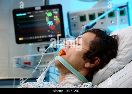 Patient in ein spezielles Bett, intubiert, medizinische Geräte für die medizinische Behandlung und künstliche Beatmung des Patienten, Stockfoto