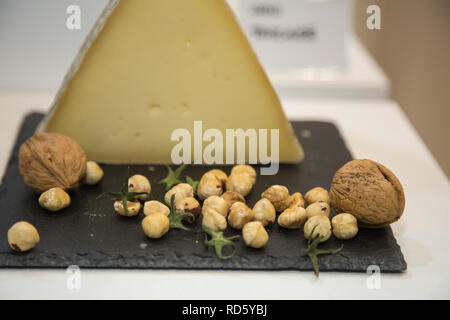 Dreieckig - Käse auf Schwarz Tischdecke mit Roh Kichererbsen und großen Walnüsse geprägt. Stockfoto