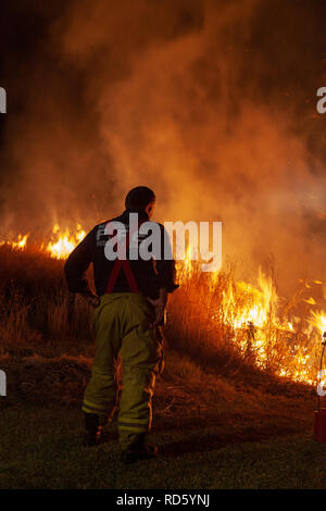 Teralba, NSW/Australien - Oktober 24, 2012: Feuerwehrmann oder Feuerwehrmann Überwachung backburning und Löschmittel ein wildfire Gras und Bushfire zu schützen r Stockfoto