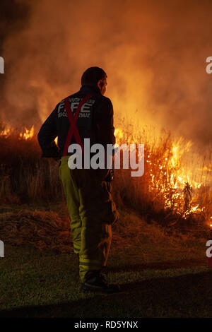 Teralba, NSW/Australien - Oktober 24, 2012: in der Nähe von Feuerwehrmann Überwachung der backburning und Löschmittel ein wildfire Gras und Bushfire zu schützen. Stockfoto