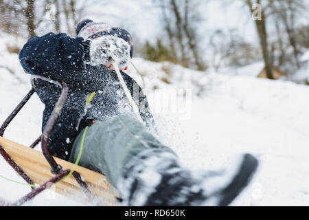 Das Kind versucht, in den Schlitten zu bleiben, um nicht zu fallen Stockfoto