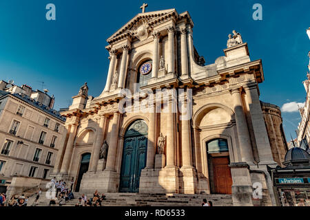 Leute sitzen auf die Schritte der Eglise Saint Roch, eine spätbarocke Katholische Kirche bei 284 rue Saint-Honoré am späten Nachmittag Sonnenschein, Paris. Stockfoto