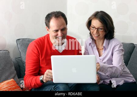 Paar, Mann, Frau, ca. 45 Jahre alt, das Surfen im Internet auf einem Laptop zu Hause Stockfoto