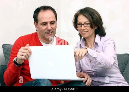 Paar, Mann, Frau, ca. 45 Jahre alt, das Surfen im Internet auf einem Laptop zu Hause Stockfoto