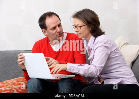 Paar, Mann, Frau, ca. 45 Jahre alt, das Surfen im Internet auf einem Laptop zu Hause Stockfoto