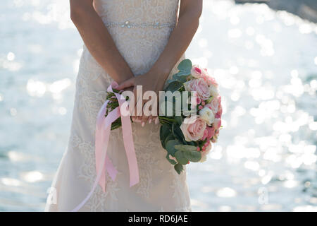 Braut hält in der Hand einen pink und white wedding bouquet auf dem Hintergrund des Meeres Stockfoto