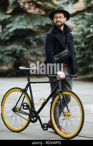 Eine junge stilvolle Hipster posiert neben seinem Fahrrad. Stockfoto