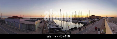 Ostia Lido Rom, Italien, 15. Januar 2019: Sonnenuntergang Panorama in der Goldenen Stunde bei touristischen Hafen in Rom, viele Segelboote vertäut sind, einige Leute an. Stockfoto