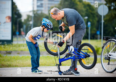 Süße kleine Junge mit seinem Vater Reparatur Fahrrad im Freien Stockfoto