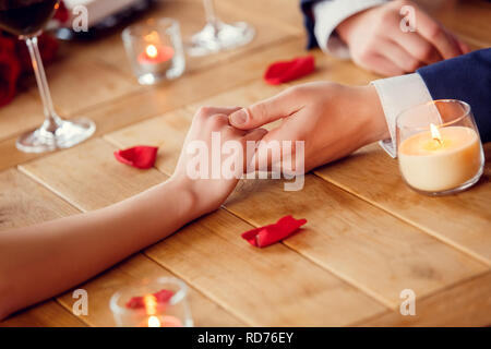 Junges Paar auf Datum im Restaurant in der Nähe sitzen, Hände halten Ausschreibung Stockfoto