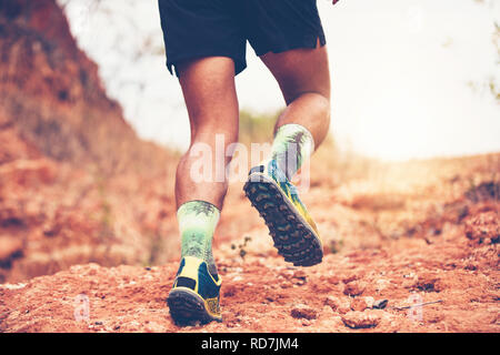 Ein Mann Runner von Trail. Und in der Nähe der Füße tragen ein Athlet Sport Schuhe für Trail Running in den Bergen Stockfoto