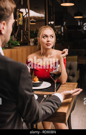 Verträumte Mädchen in der Nähe von süßen Nachtisch sitzen mit Freund im Restaurant Stockfoto