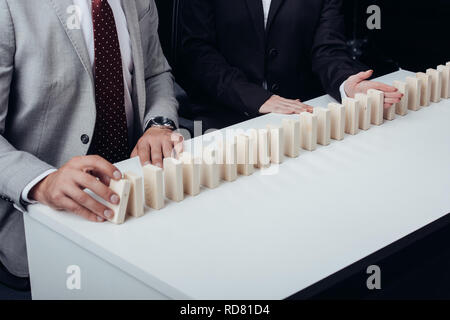 7/8-Ansicht des Menschen drücken Holz- Ziegel, während Frau verhindern Reihe fallen. Stockfoto