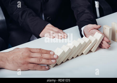 7/8-Ansicht des Menschen drücken Holz- Ziegel, während Frau verhindern Reihe fallen. Stockfoto