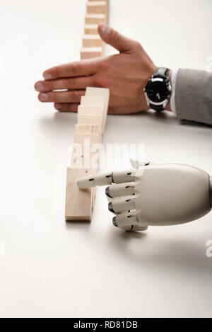 7/8-Ansicht der Roboterhand drücken Holz- Ziegel während man verhindern Reihe fallen. Stockfoto