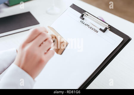 Selektiver Fokus der Zwischenablage mit Visa Application Beschriftung auf dem Dokument in der Hand der weiblichen Rechtsanwalt Stockfoto