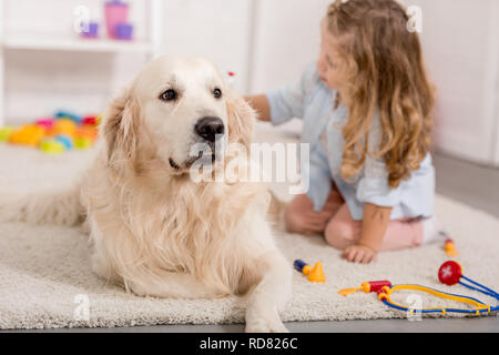 Adorable kid vorgibt, Tierarzt und Prüfung der Golden Retriever Hund im Kinderzimmer Stockfoto