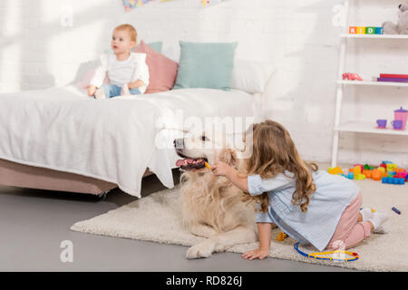 Adorable kid vorgibt, Tierarzt und Prüfung der Golden Retriever im Kinderzimmer Stockfoto