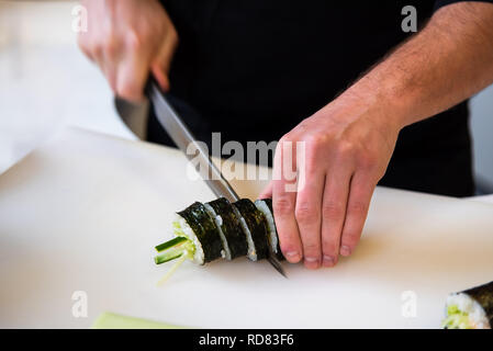 Koch Schneiden von sushi Rollen in der Bar Stockfoto