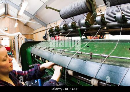 Hoch qualifizierte schwedische Frau mit restaurierten Wolle und Textilmaschinen aus dem 19. Jahrhundert eine Produktionslinie von nachhaltig produzierten Wolle und Textilwaren. Stockfoto