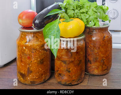Verschiedene Gemüse in Gläsern mit abgedichteten Metallgehäuse mit Deckel: Auberginen, Paprika, Tomaten, Zwiebeln bewahrt. Frisches Gemüse und Salat sind in der Nähe von Stockfoto