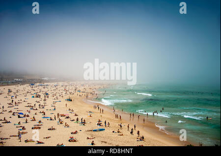 Meer Nebel umhüllt die Szene am Bondi Beach, Sydney, NSW, Australien. Menschen Entspannung am Sandstrand mit blauen Meer/Himmel Hintergrund Stockfoto