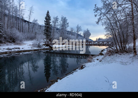 Ein weiches Abendlicht senkt sich über die Fußgängerbrücke am Tag eines Winter bei Eklutna Tailrace, Alaska Stockfoto