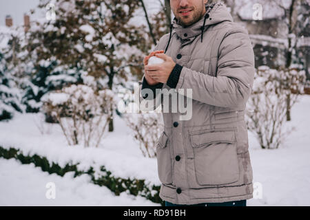 7/8-Ansicht der Mann hält Schneeball in die Hände im Winter Stockfoto