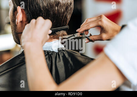 Close-up Teilansicht der Friseur kämmen und Haare schneiden für junge Menschen