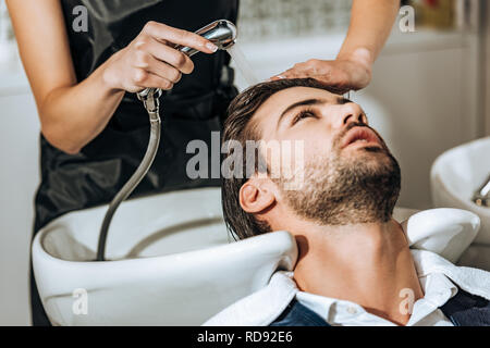 Teilweise mit Blick auf die Friseur Haare waschen zu stattlichen jungen männlichen Klienten im Beauty Salon Stockfoto