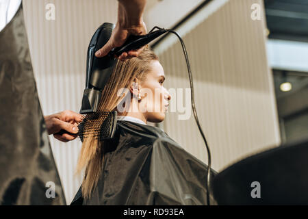 Low Angle View der Friseur Haare trocknen zu attraktiven Mädchen im Beauty Salon Stockfoto