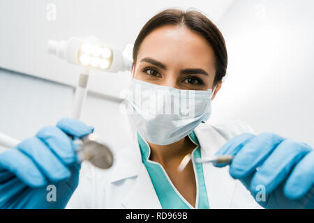 Selektiver Fokus der weiblichen Zahnarzt in Maske holding Instrumente in den Händen Stockfoto