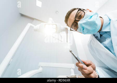 Afrikanische amerikanische Zahnarzt im weißen Mantel und Maske mit Bohrer in der Hand Stockfoto