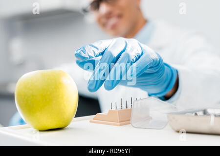 Selektiver Fokus der Hand der männlichen afrikanischen amerikanischen Zahnarzt latex Handschuh in der Nähe lecker Apple Stockfoto