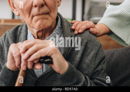 7/8-Ansicht der pensionierten Ehemann im Wohnzimmer und in der Nähe der älteren Frau sitzen Stockfoto