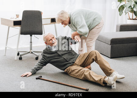 Alte Frau vor, die für den Mann, der sich auf dem Boden stehen, falled Stockfoto